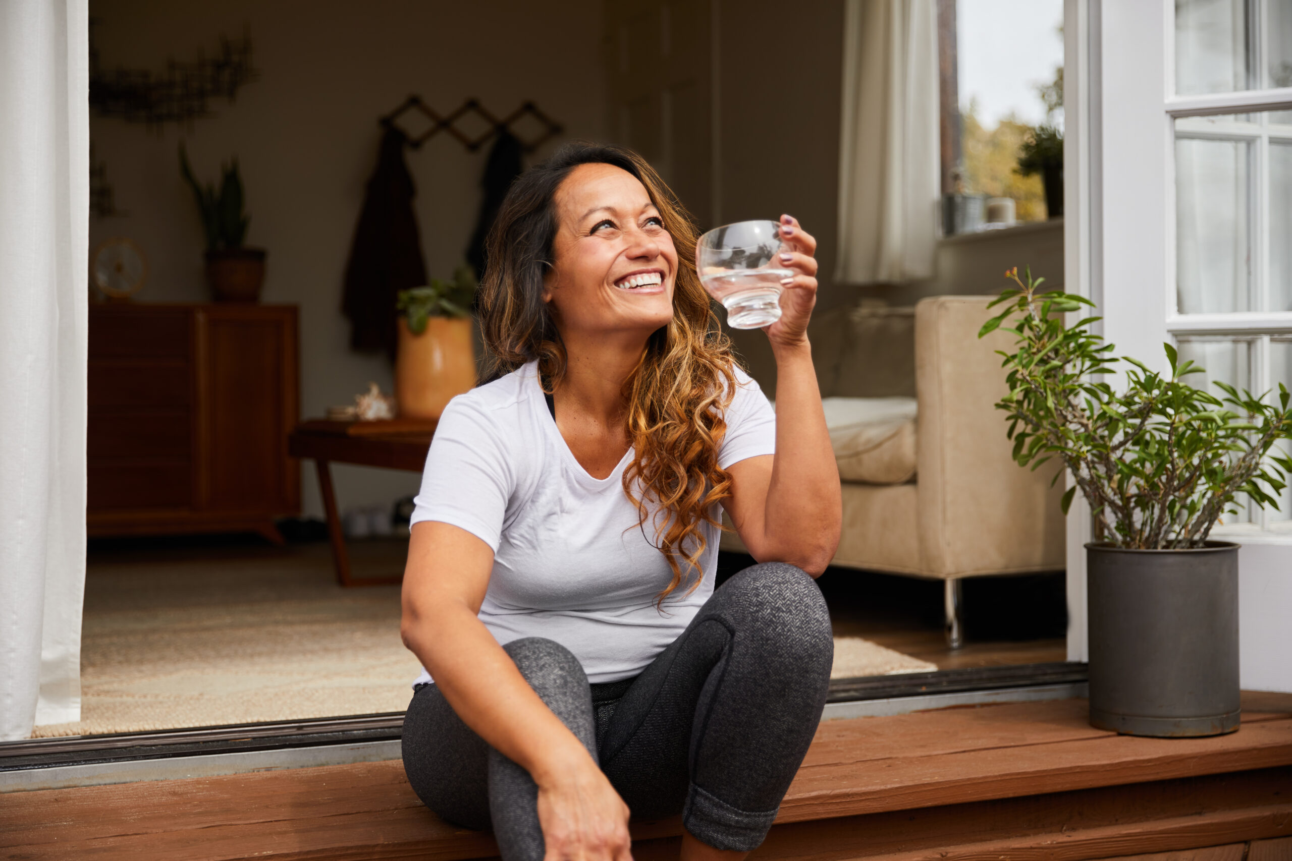 Smiling mature woman sitting on her patio drinking water